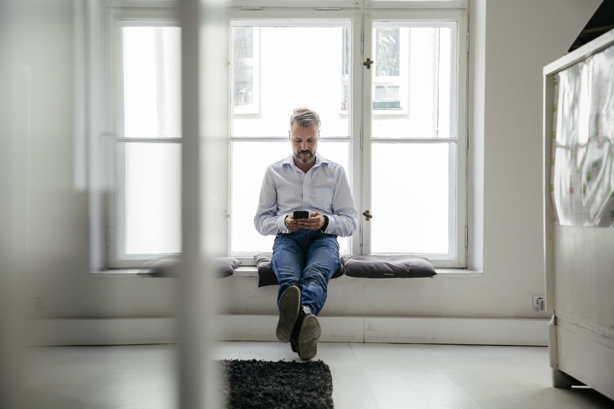 oppsigelse av leder - en mann sitter i vinduskarmen og ser på telefon