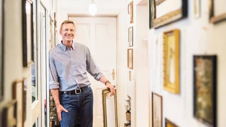 skatt ved salg av tomt - mann som står i en gang med mange bilder