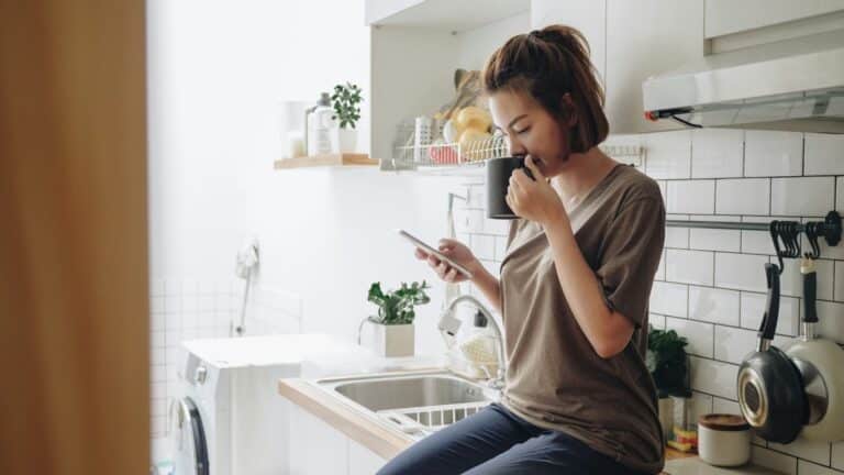 husleieavtale og leieavtale - kvinne sitter på kjøkkenbenken og drikker en kopp te