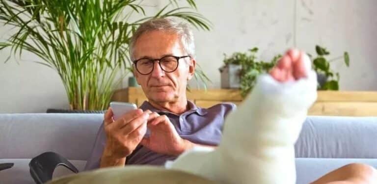 sykepenger fra nav - mann sitter i sofaen med knekt fot