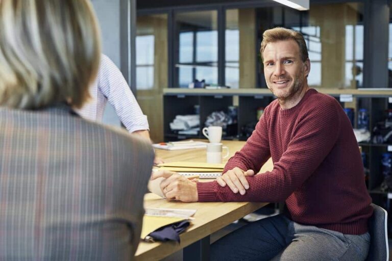 selskapsrett - mann ser i kamera i et kontorlandskap